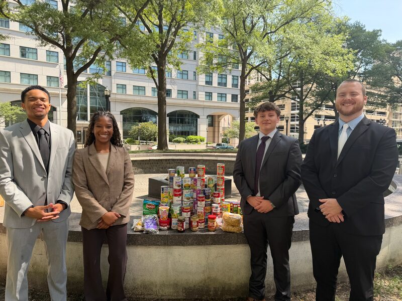 Legacy Point Solutions team members beside canned goods collected in a community food drive